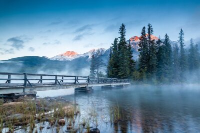 Holzbrücke über einem See inmitten von Bergen