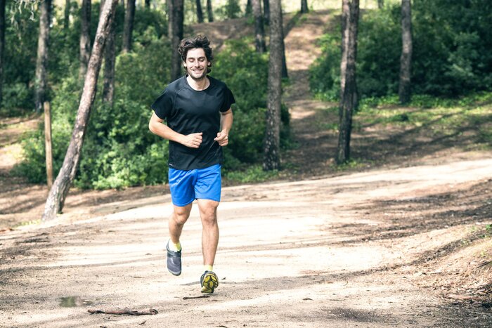Poster Mann läuft entlang eines Waldweges