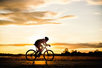 Mensch und Fahrrad vor dem Hintergrund der untergehenden Sonne