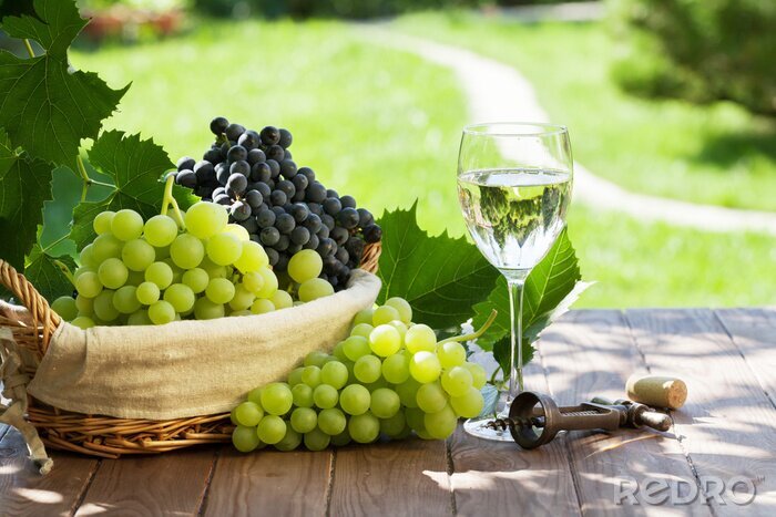 Poster Weißwein neben einem Korb mit Weintrauben