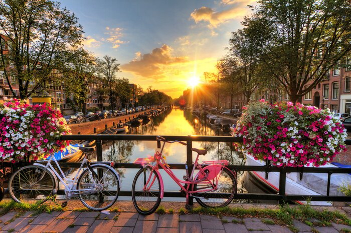 Sticker Beautiful sunrise over Amsterdam, The Netherlands, with flowers and bicycles on the bridge in spring