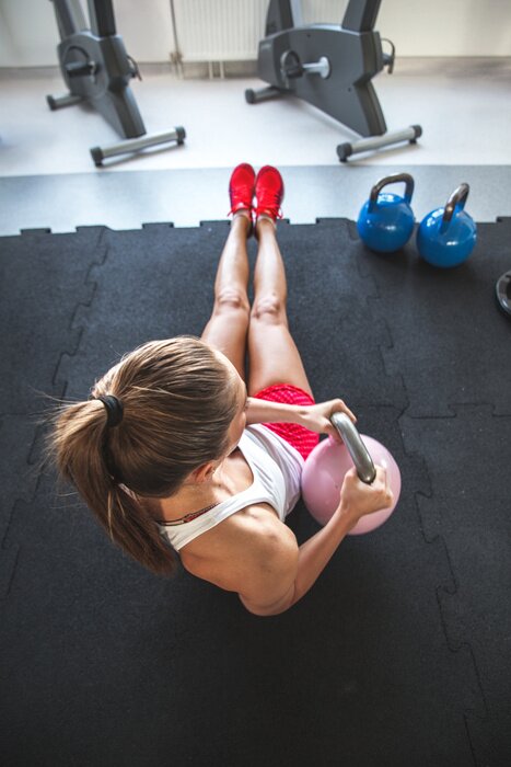 Sticker Frau arbeitet an ihrem abs mit Kettlebell
