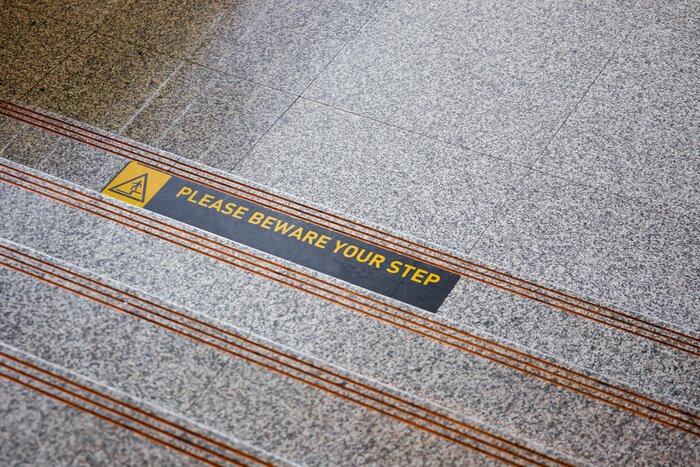 Sticker Please beware your step sticker on polished stone floor close up.